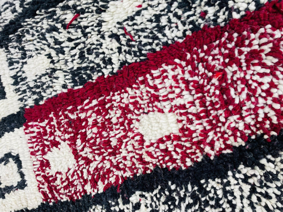 Detail view of a red and black Moroccan rug with a textured surface.