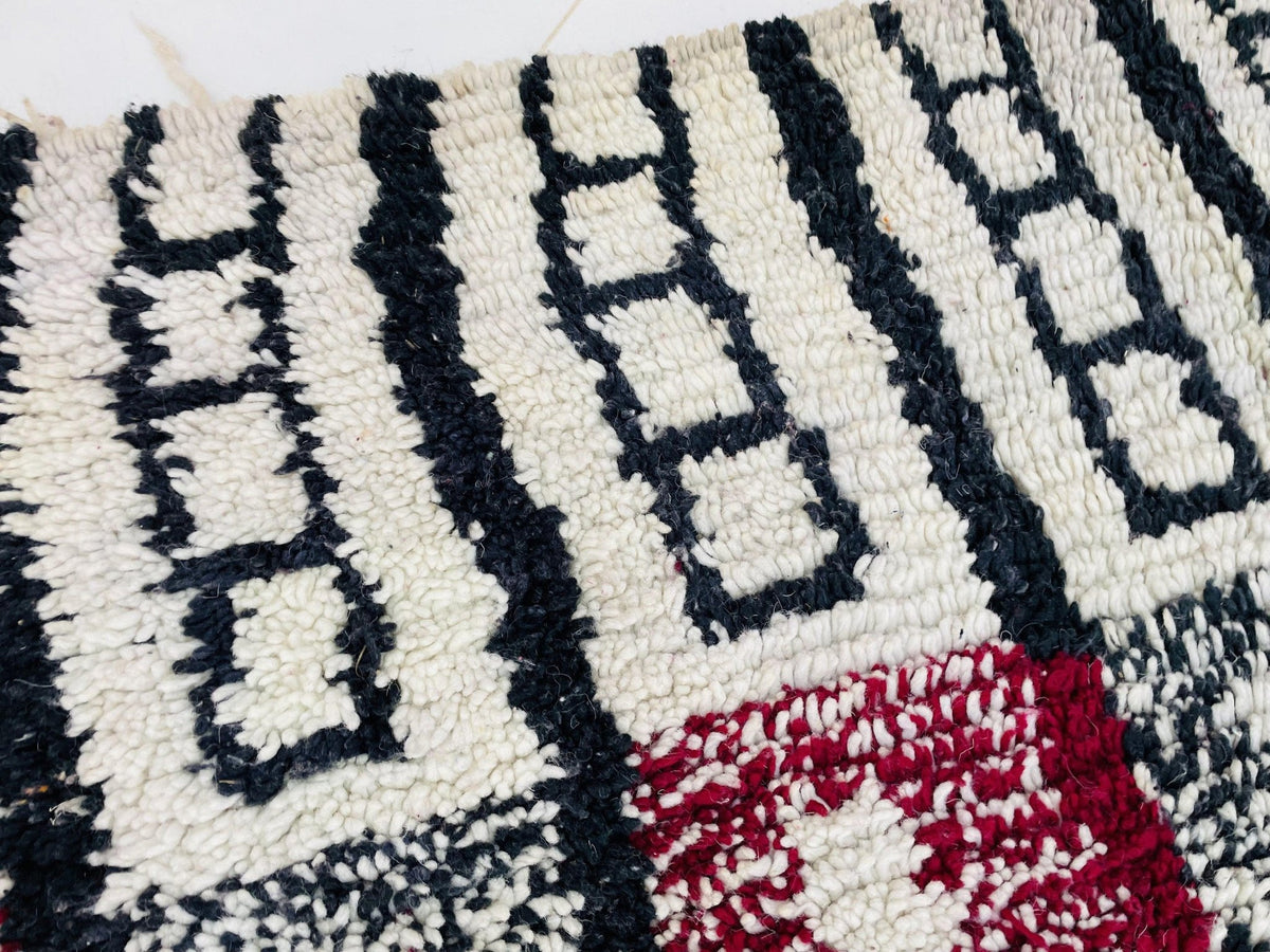 Close-up of a patterned Moroccan rug showcasing an abstract design in black, white, and red.