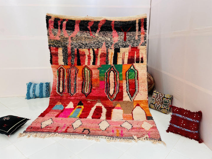Lifestyle shot of a vintage Moroccan rug featuring red, pink, blue, and green colors.