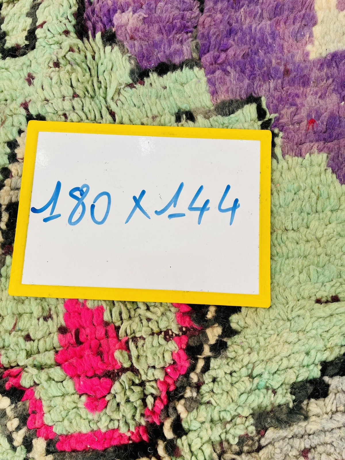Detail shot of the rug label showing size information with handwritten text in yellow and blue.