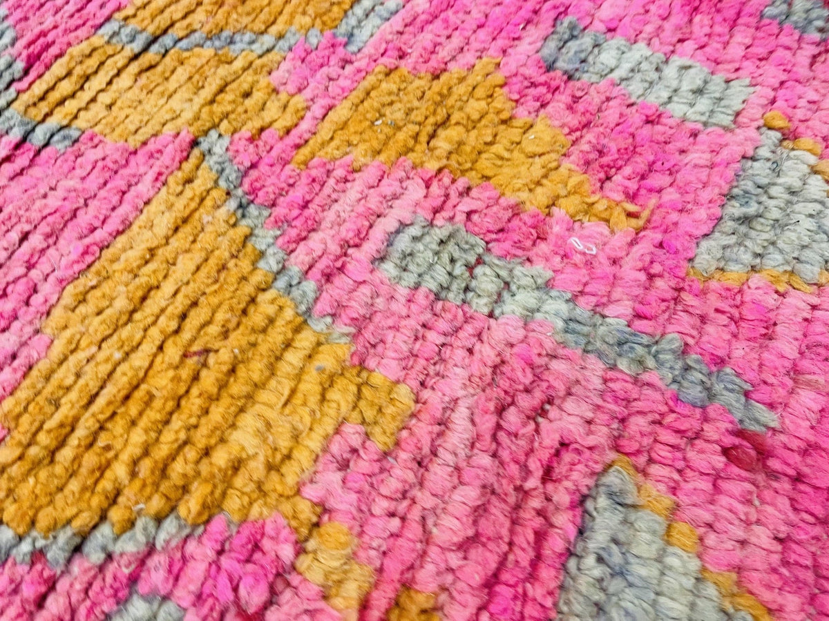 Detail shot of a pink Moroccan rug focusing on its abstract design.