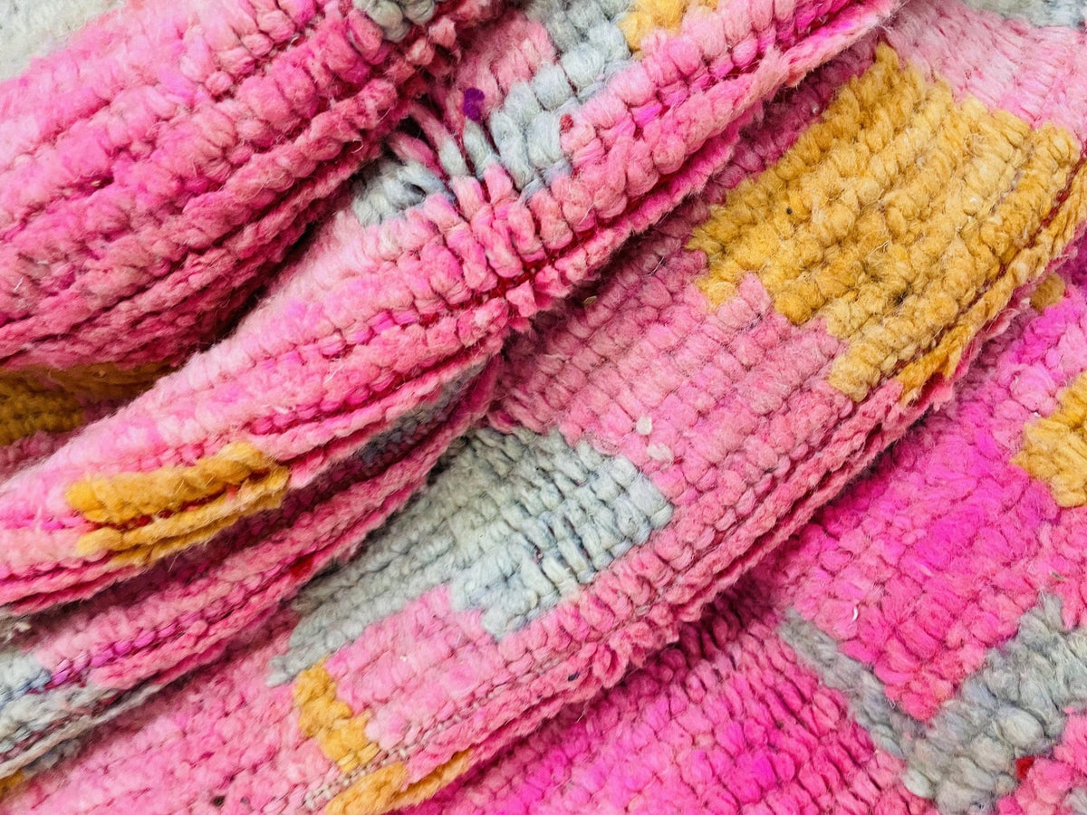 Front view of a pink Moroccan rug showcasing traditional patterns in a studio.