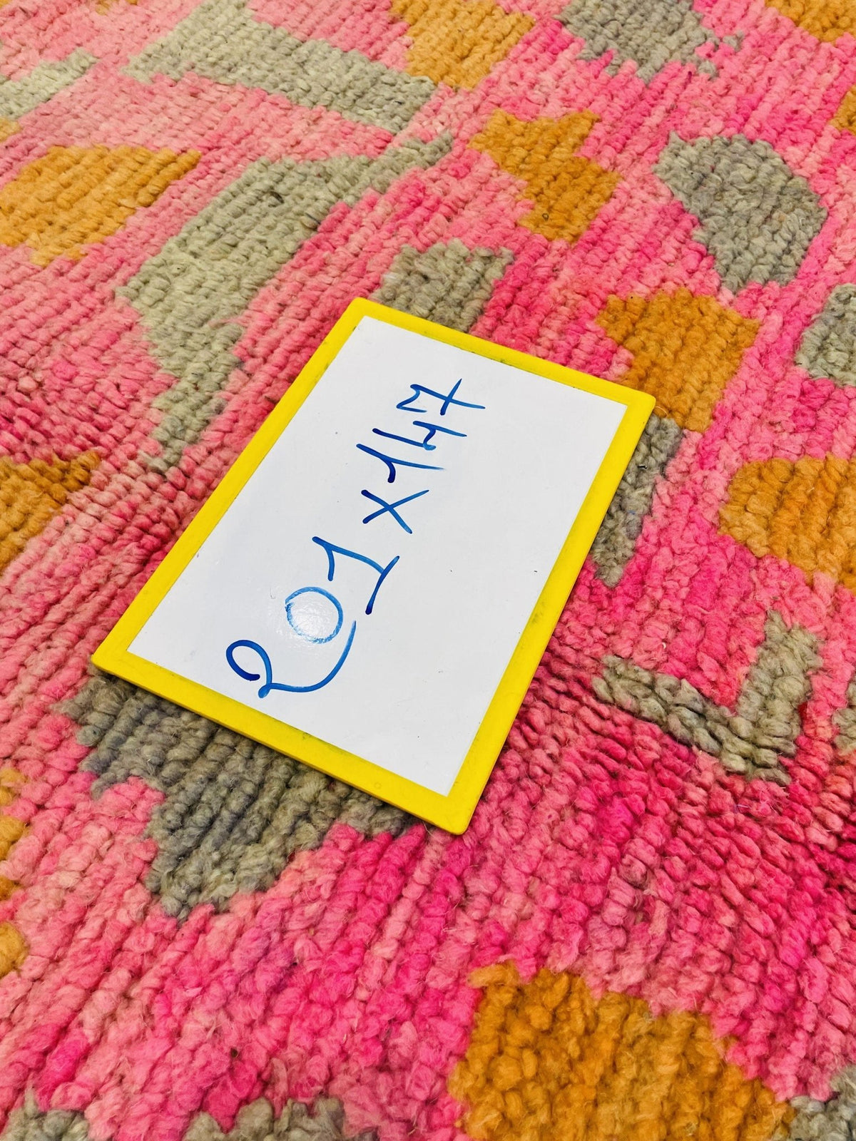 Detail shot showing a tag on a pink Moroccan rug with handwritten text.