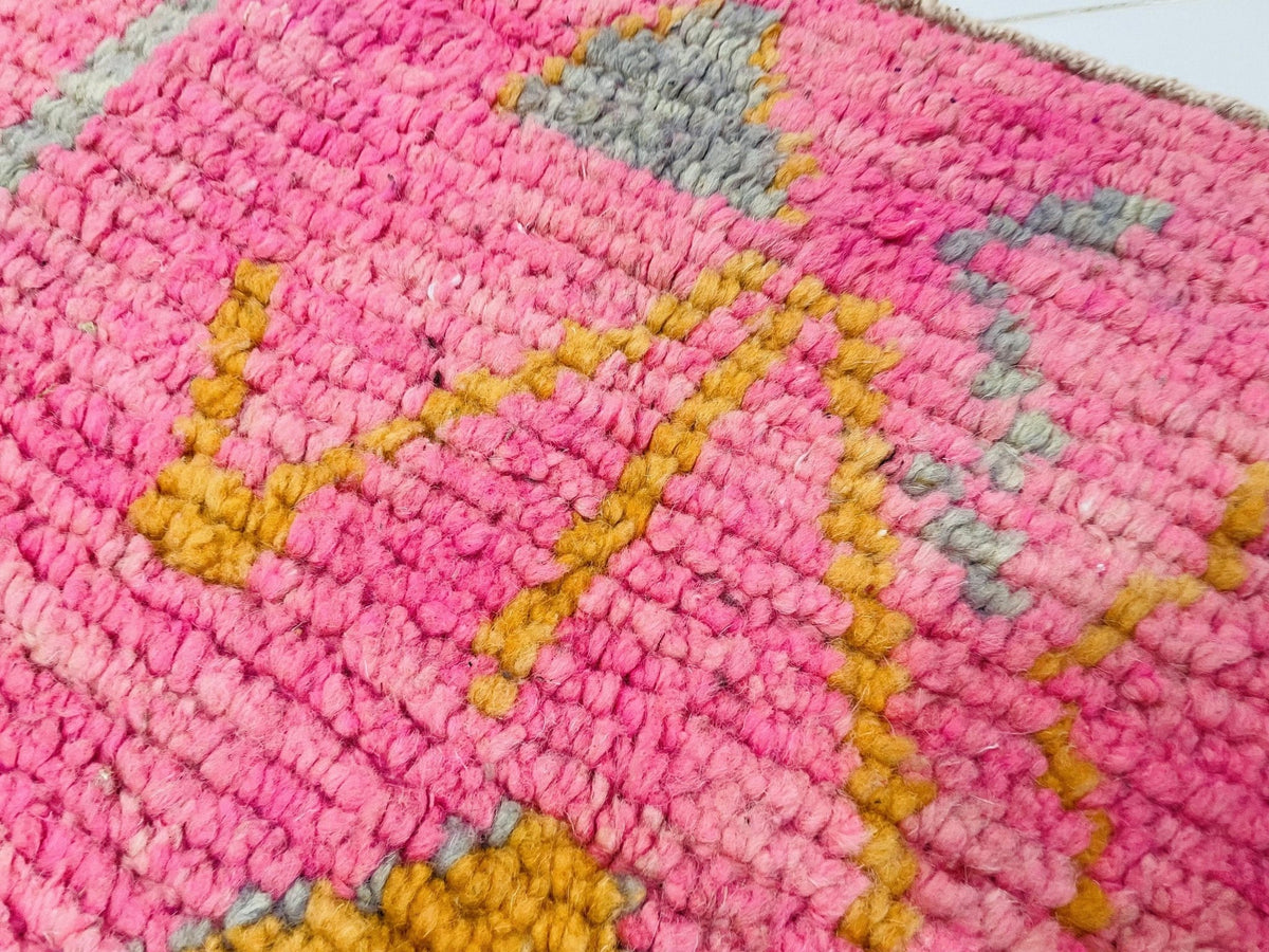 Close-up view of a pink Moroccan rug featuring an abstract pattern.
