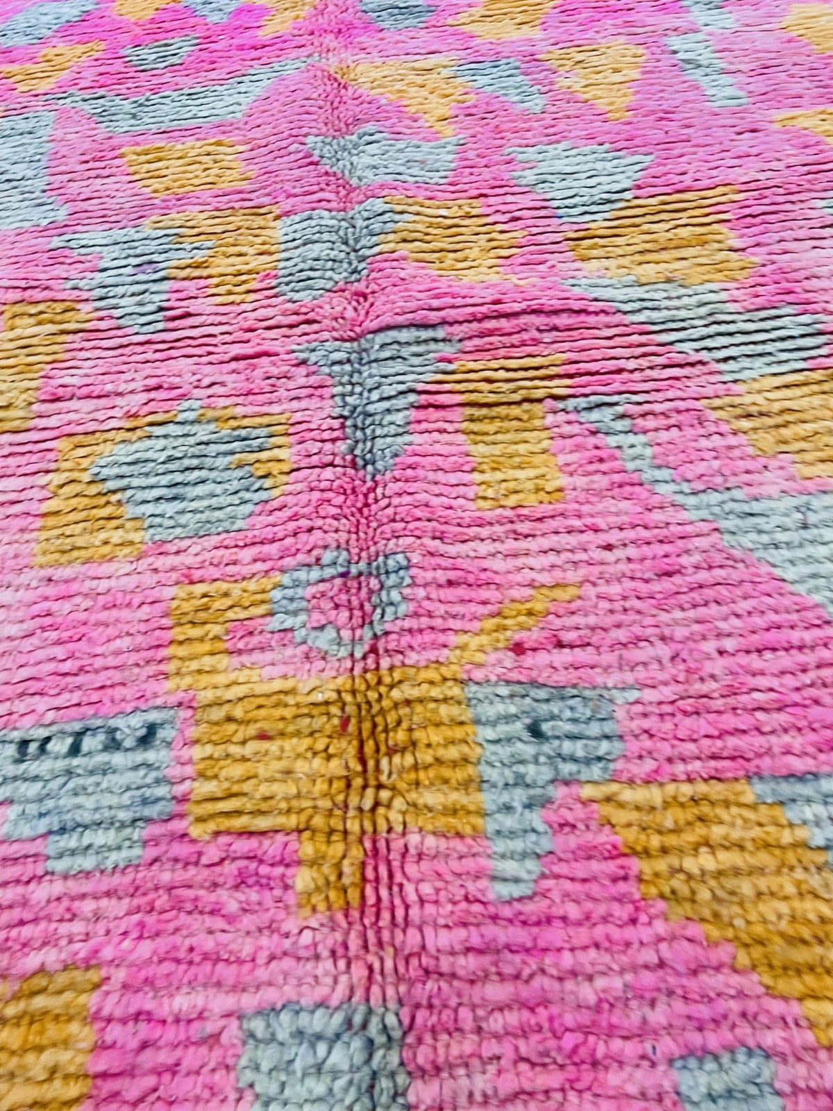 Close-up detail of a pink Moroccan rug emphasizing its abstract pattern.
