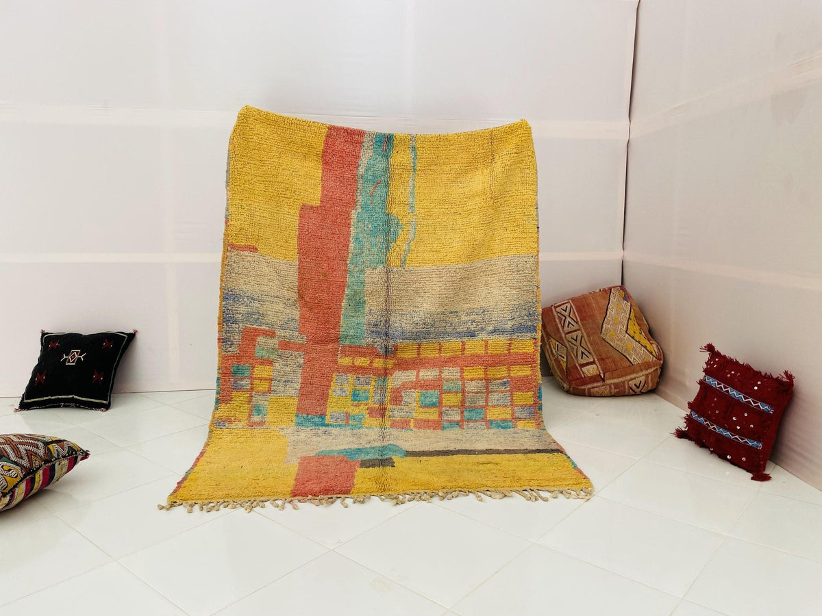 Lifestyle shot of a vintage Moroccan rug featuring yellow and red colors on a white background.