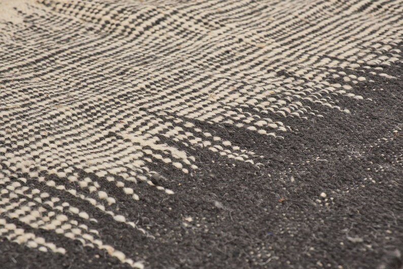 Close-up detail of the woven pattern on the black and gray striped Kilim rug.