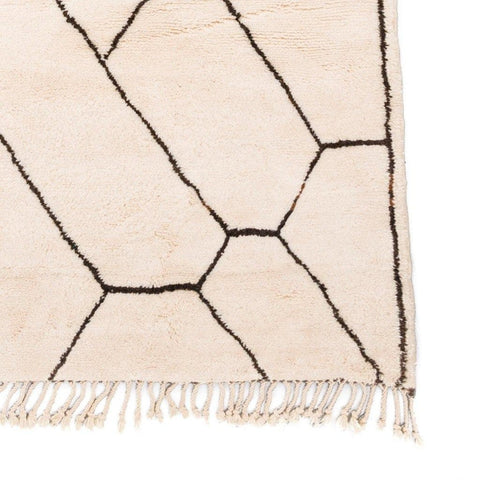 Detail shot of the edge of the geometric rug featuring fringe edges.