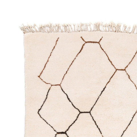 Close-up detail of the geometric rug with fringe detail in black, white, and brown.