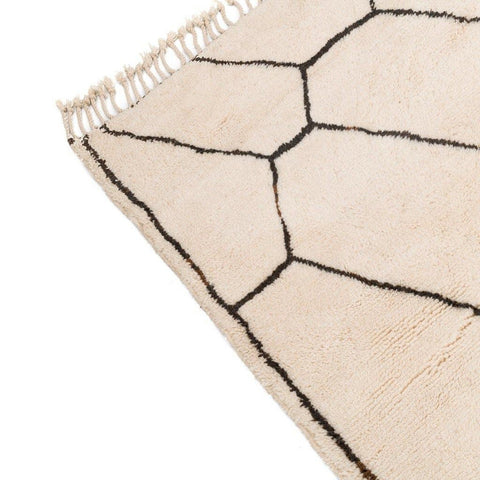 Close-up of the white area rug with a fringe edge and geometric pattern.