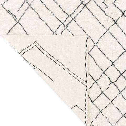 Detail view of the geometric white area rug from a corner perspective.