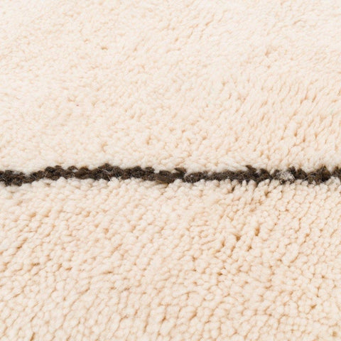 Detail view of the white area rug featuring black line details.