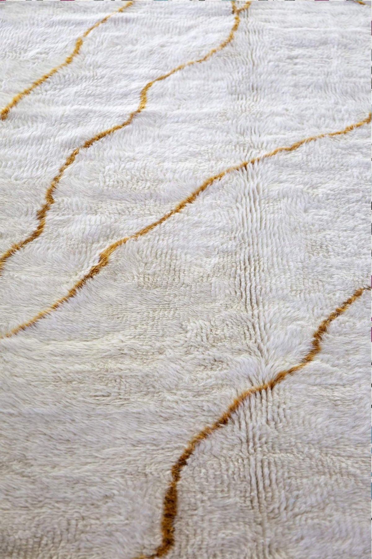 Close-up detail showing gold streaks on the soft fabric of the abstract rug.