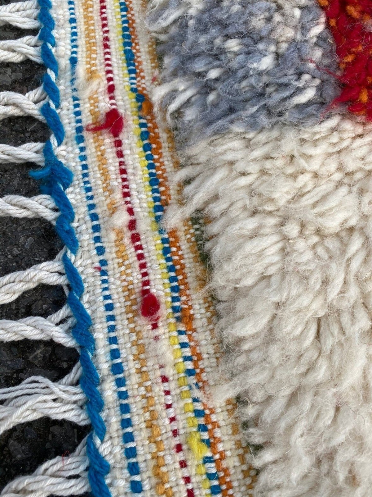 Side view of a colorful Moroccan rug showcasing geometric patterns and fringed edges.