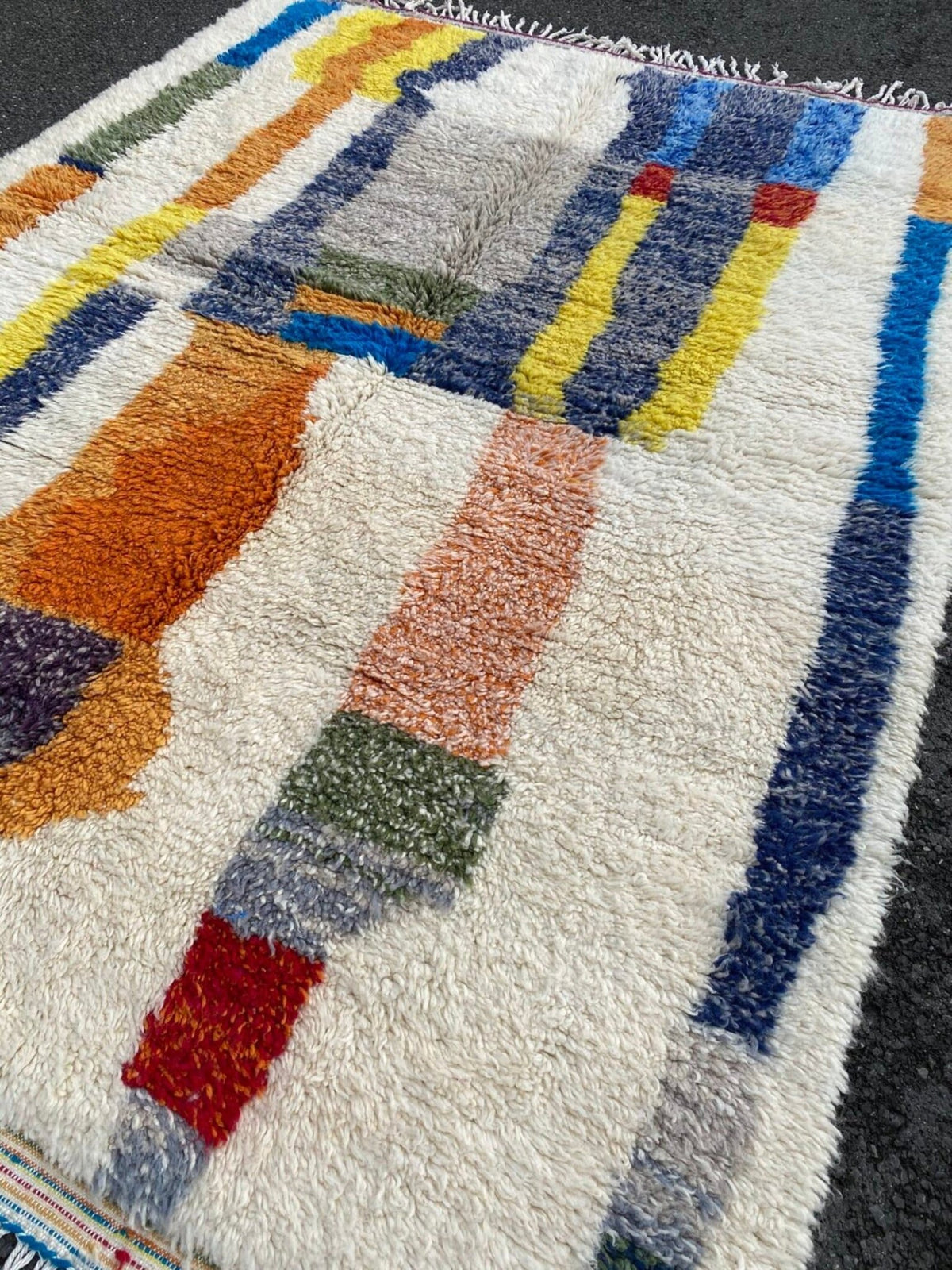 Close-up detail of a rug edge with colorful stitching and fringed edges.