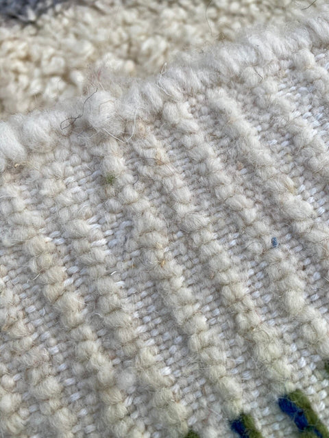 Detail view of a white Moroccan rug with a textured pattern and Berber design.