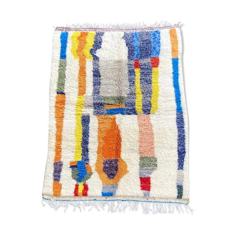 Detail view of a colorful Moroccan rug with geometric patterns and fringed edges.