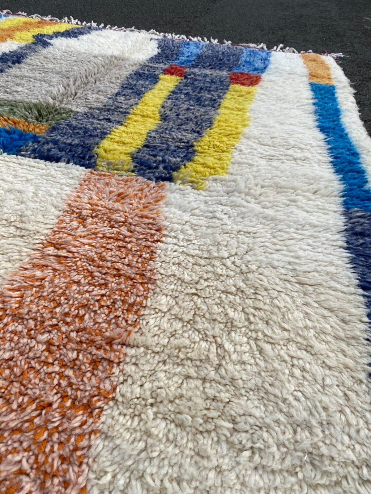Front view of a colorful Moroccan rug featuring an abstract design and fringed edges.
