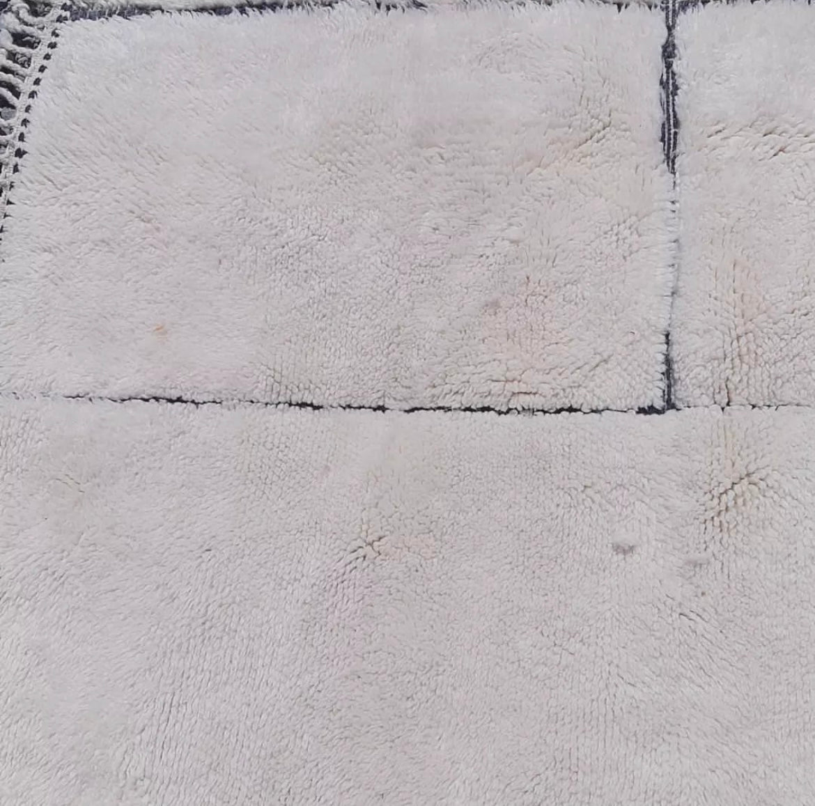 Detail view of a white Moroccan rug, capturing its design and texture.