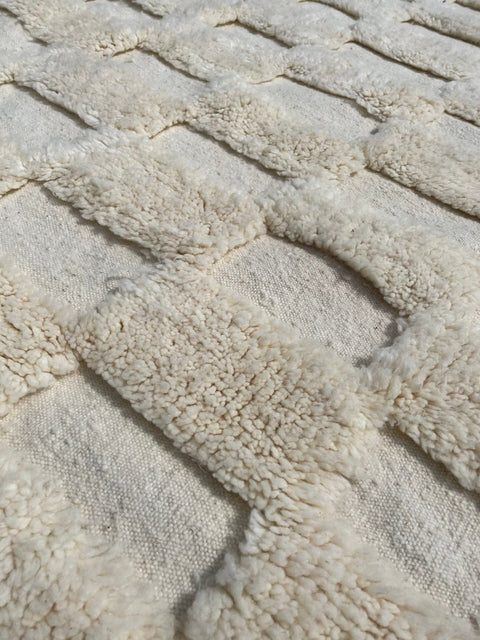 Detail close-up of a white checkered rug with a tufted texture.