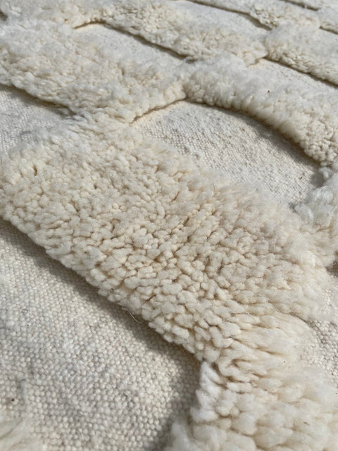 Detail close-up of a checkered Moroccan rug in white and cream colors.