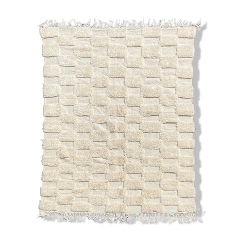 Detail close-up of a checkered Moroccan rug in white and beige colors.