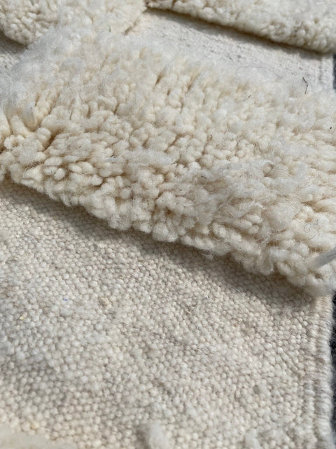 Detail close-up of a white checkered rug highlighting tufted texture.