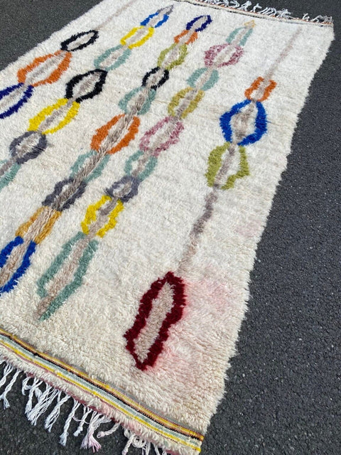 Front view of a pastel multicolor bohemian rug showcasing geometric patterns and fringe edges.