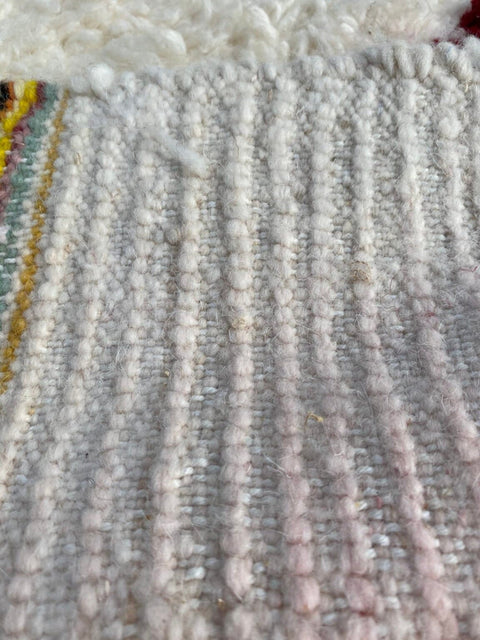 Close-up detail of a bohemian rug with a textured surface and colorful threads.