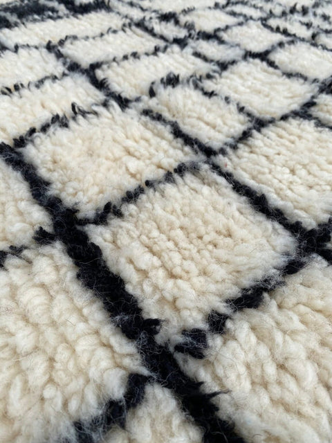 Detailed shot of a black and white rug featuring a plush texture and grid pattern.