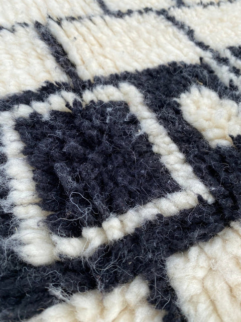 Close-up of a black and white rug highlighting its textured surface and geometric pattern.