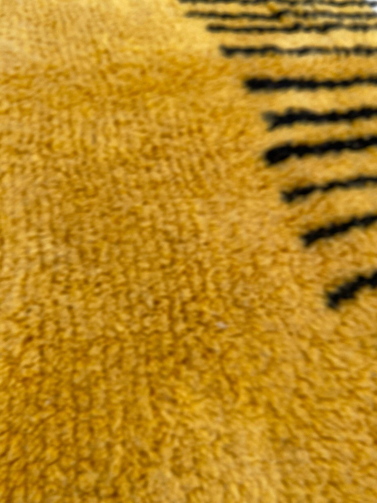 Close-up detail of the yellow and black rug highlighting its soft texture and stripes.