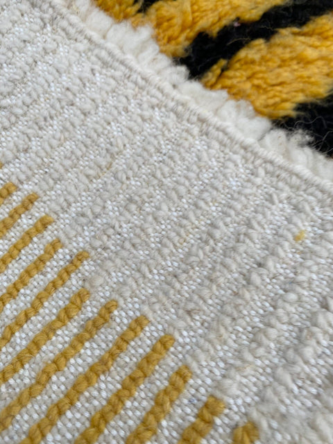 Close-up detail of the edge of the yellow and black striped rug.