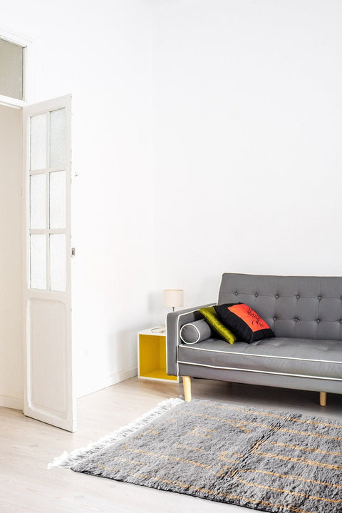 Lifestyle shot of a living room featuring the gray Moroccan rug with a sofa and decorative pillows.