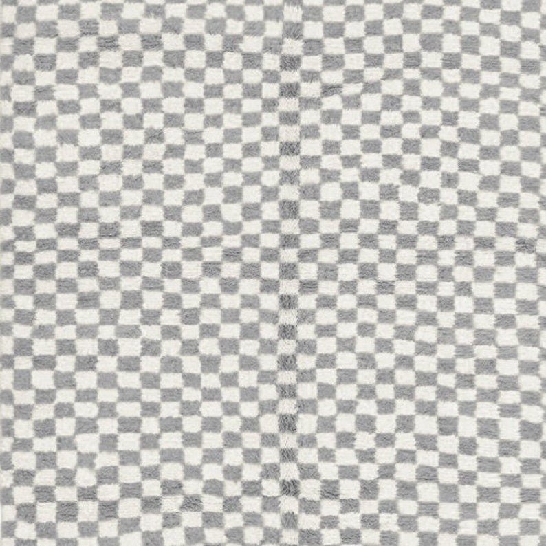 Close-up detail of the gray checkered Moroccan rug's texture on a white background.