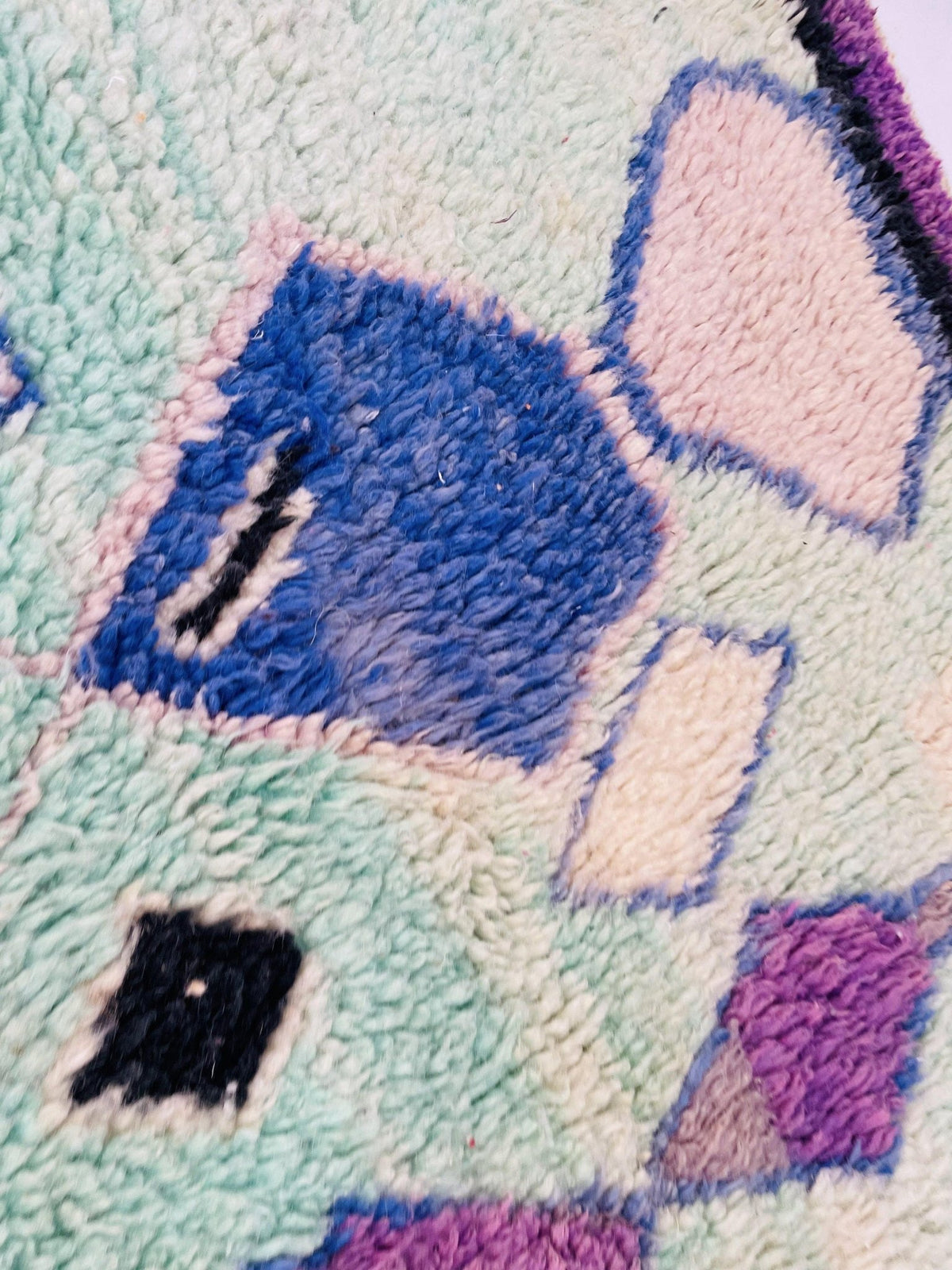 Close-up of the textured surface and tribal designs on the green and purple Boujaad Moroccan rug.