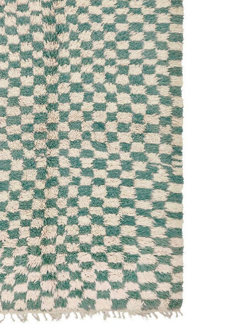 Close-up detail of the green checkered rug emphasizing its unique tribal pattern.