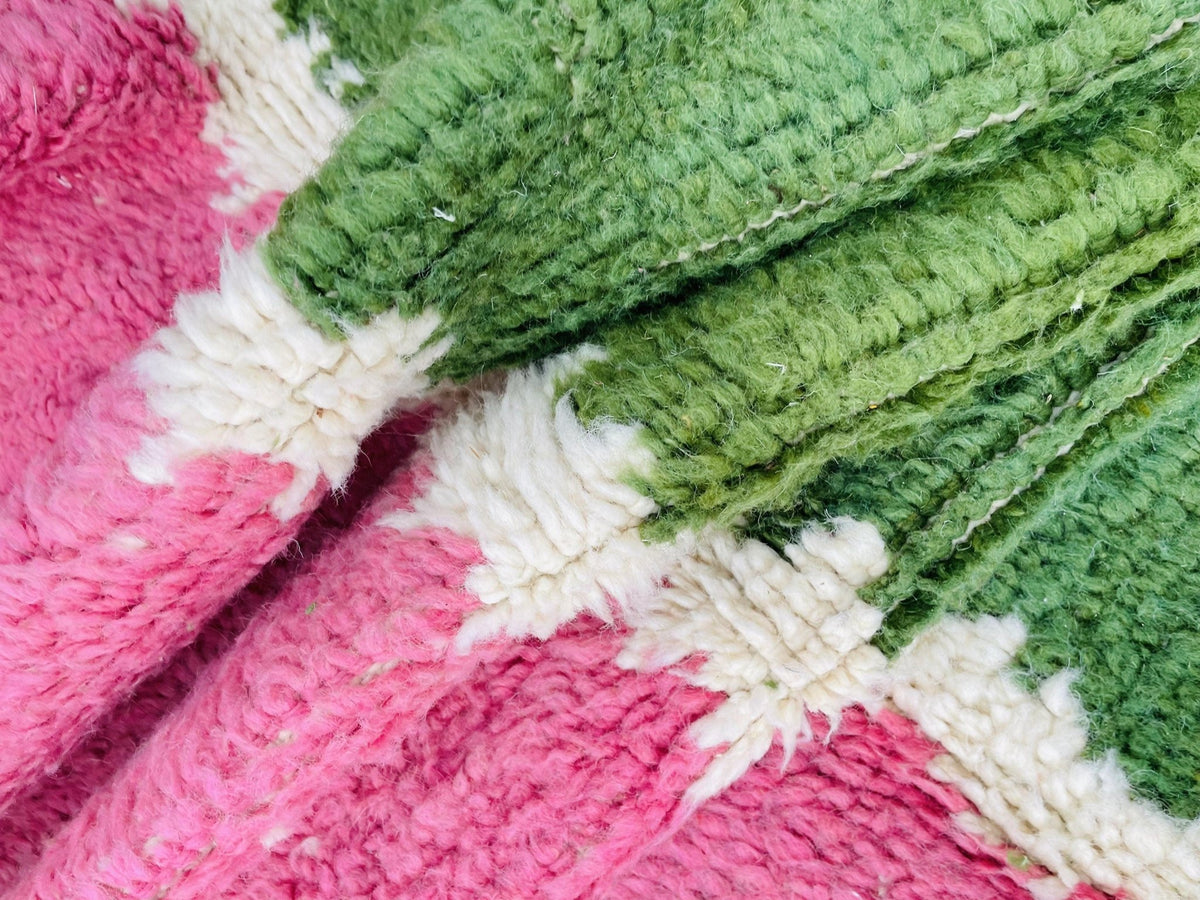 Detail close-up of the colorful pattern on a green and pink vintage Moroccan rug.