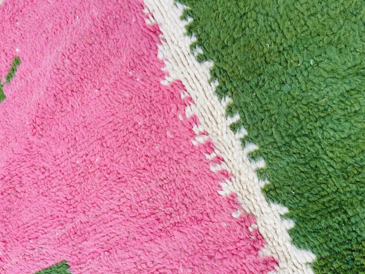 Detail close-up of a pink and green vintage rug with a textured pattern.