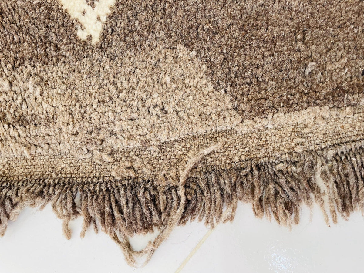 Lifestyle shot of a brown and cream vintage Moroccan rug showcasing abstract patterns and fringe edges.