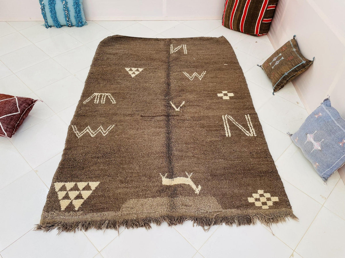 Close-up detail of the woven texture of a brown and cream vintage Moroccan rug with fringe edges.