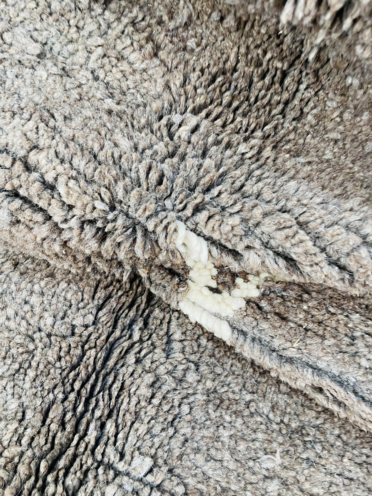 Lifestyle view of a grey and brown vintage Moroccan rug featuring abstract patterns and fringe edges.