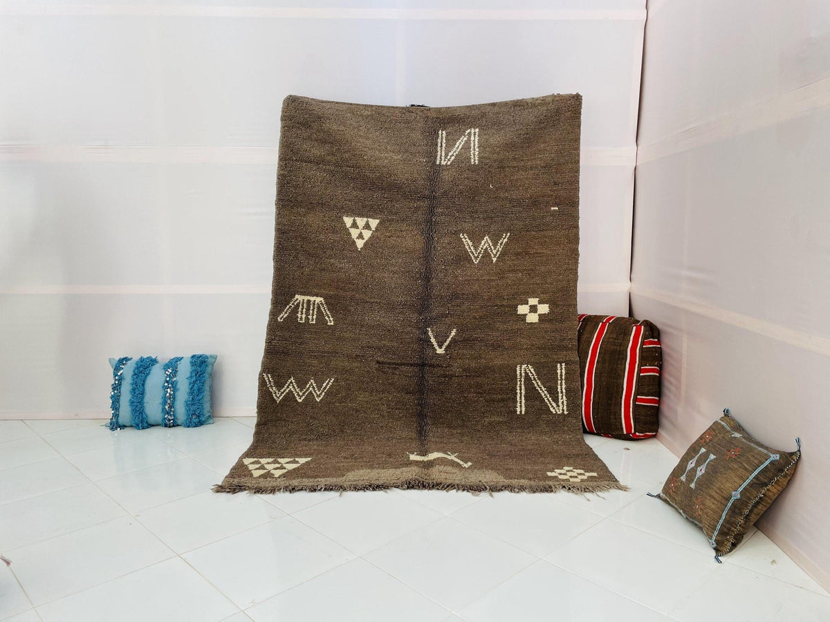 Lifestyle shot of a grey and brown vintage Moroccan rug with abstract patterns and fringe edges.