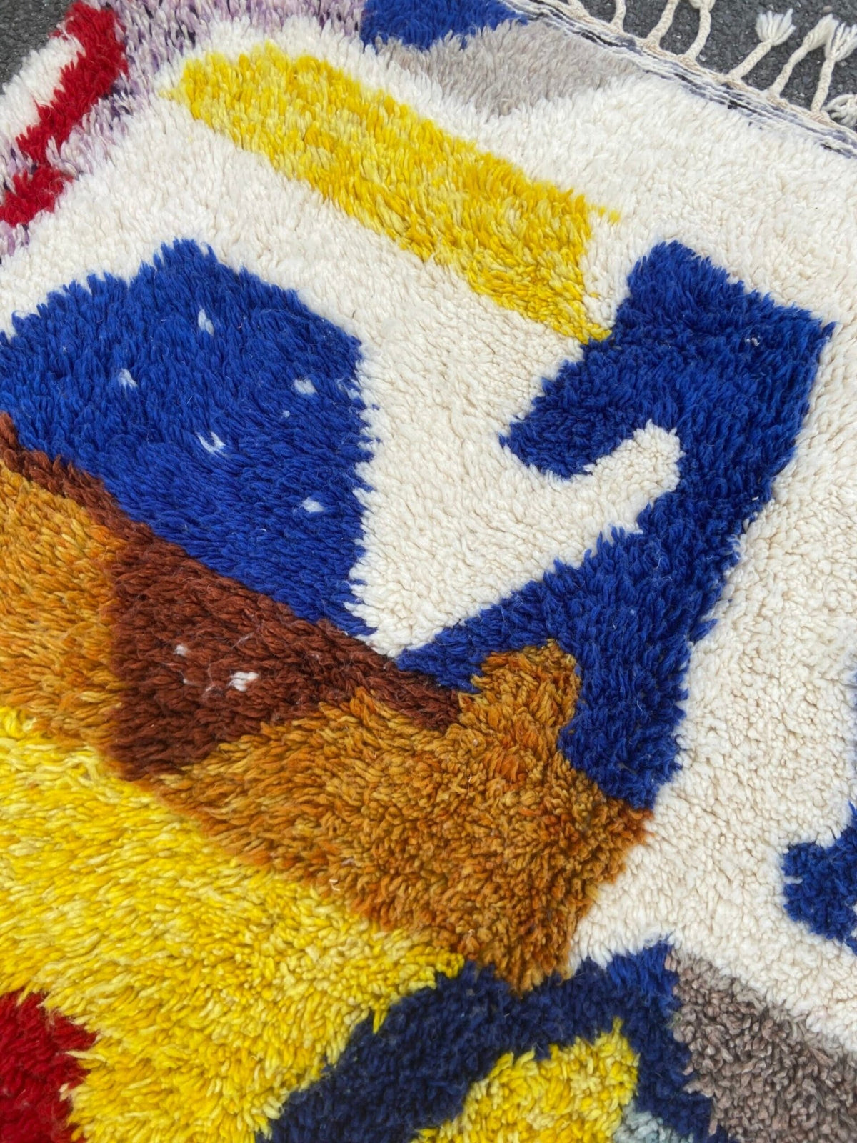 Close-up detail of a handwoven rug with a textured pattern and vibrant colors.