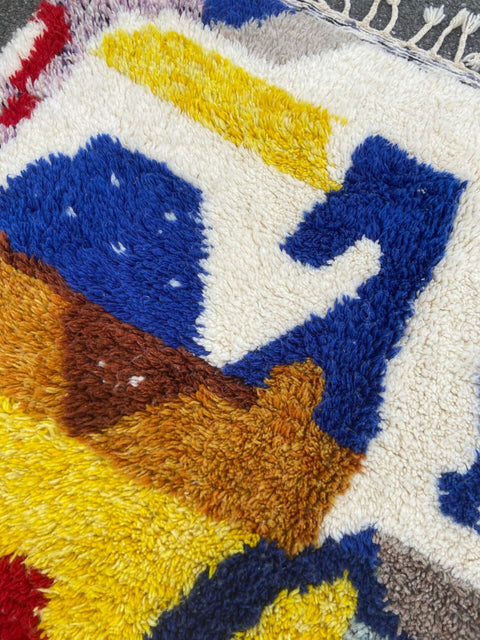 Close-up detail of a handwoven rug with a textured pattern and vibrant colors.