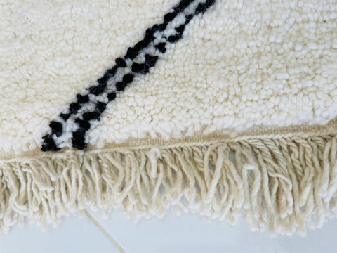 Close-up detail of the fringed edge of a Moroccan rug with a soft texture.