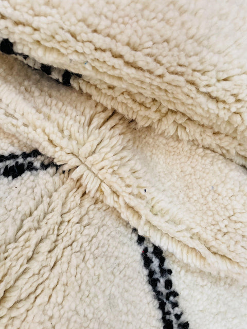 Lifestyle view of a Moroccan rug with a diamond design in white and black colors.