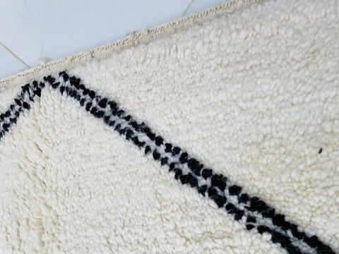 Detail shot of a white rug with a black geometric design and textured surface.