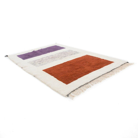 Side view of the cream and burgundy color block Moroccan rug showcasing its layered design.