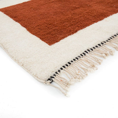 Detail close-up of the cream and burgundy color block geometric pattern rug with fringe.